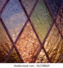 lIght reflected in leaded. diamond pattern, stained glass window, orange, green, brown, blue