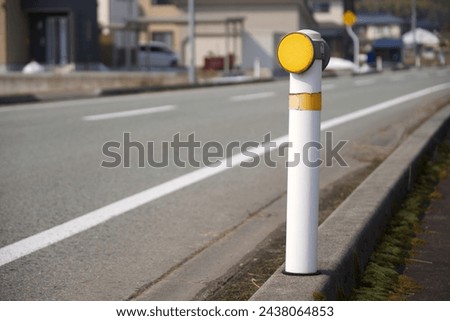 A light reflector located on a the side of a curvey road.