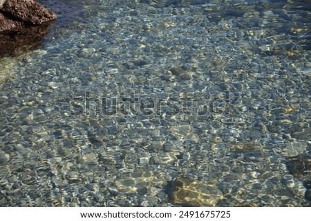 Light refracts through deceptively deep, crystal-clear water in Mali Losinj, Croatia.Pebbles stones in transparent water.Clear water reveals an array of smooth pebble stones beneath the surface.