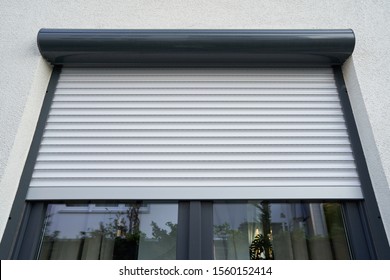 Light roller shutter curtains mounted on a dark window