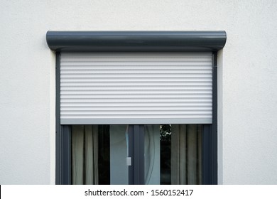 Light roller shutter curtains mounted on a dark window