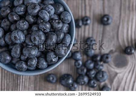 The light of the setting sun casts long shadows of the blueberries on the wood, creating a play of light and shadow that accentuates their volume