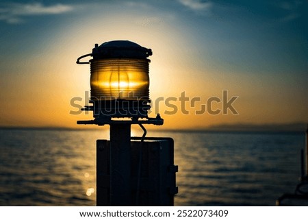 The light of the setting sun filters through a storm lamp, in the background the transition of the sea and blue clouds to the light of the yellow sun.