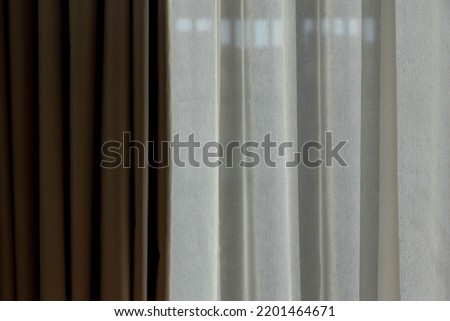 Light and shadow concept, Classic see through white sheer curtains hanging by the window in the room with sunlight and blurred outside view, Fabric and linen background.