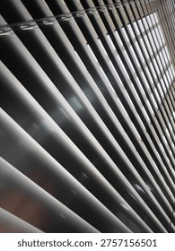 Light and Shadow Play Through Window Blinds Creating Abstract Patterns. This image captures the interplay of light and shadow created by window blinds. 