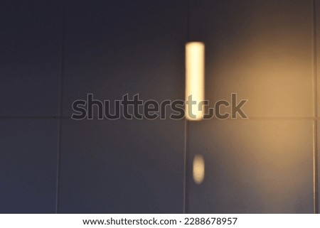 Light shaped exclamation mark transmuting sunset lights onto white matt tiles