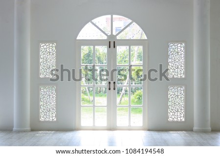 The light shines on the white door. When look outside, there is a green tree. Look so refresh.