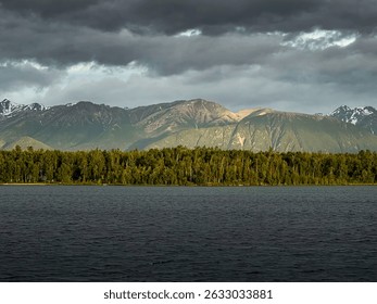 Light shining through dark clouds on mountain behind Lake Lucille on a spring night in Alaska.