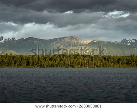 Light shining through dark clouds on mountain behind Lake Lucille on a spring night in Alaska.