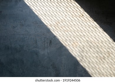 Light spilled through the steel wire of railings or baluster.Saw a shadow on raw concrete floor like net texture to strip of shadow on cement.