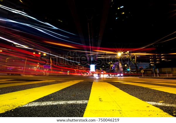 Light\
streaks from cars flying past a crossing at\
night