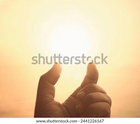 The light of the sun at fingertips. Present creative idea. Hand and warm sky background. Making big things smaller.