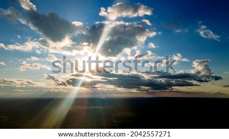 The light of the sun shining through the clouds in the sky. Amazing of fluffy clouds moving softly on the sky and the sun shining through the clouds with beautiful rays and lens flare.