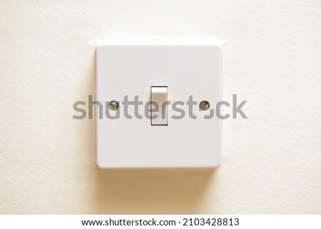 Light switch in on position on a white wall