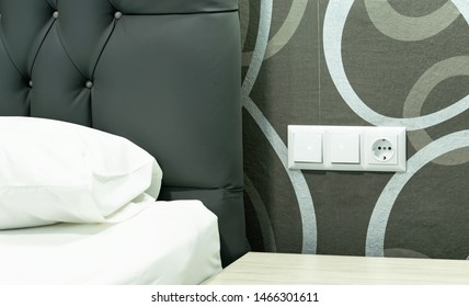 Light Switch And Socket On Decorated Wall Over The Nightstand By The Bed.