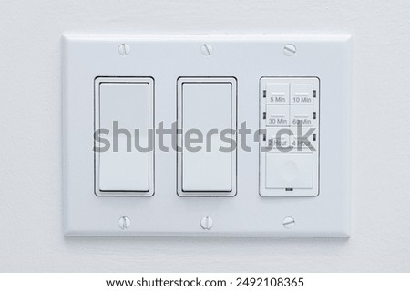 Light switch with steam shower timer switch - white wall close up.