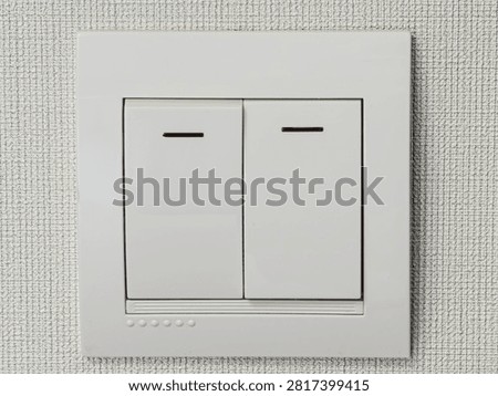 Light switch white plastic electrical key toggle on modern apartment wallpaper view.