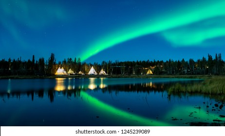 Light up Tipi (indian Tent) with water reflection during Aurora Borealis (Northern Light) at Yellow Knife, Canada