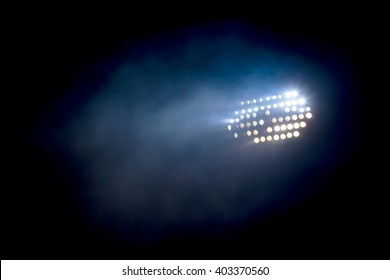 Light tower lit at a stadium during nightime.