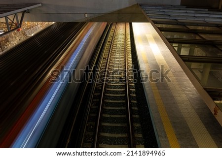 Light trail of quickly driving metro train at night in Athens, Greece with a platform and second railroad