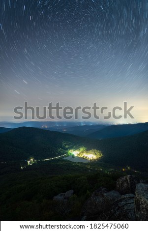 Light trails atop Sharp Top Mountain of Peaks of Otter looking down at the Peaks of Otter Lodge and Abbott Lake.