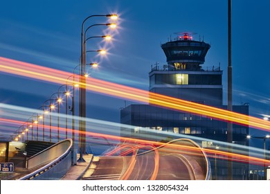 Light Trails Of The Cars On The Road To Airport Against Air Traffic Control Tower.