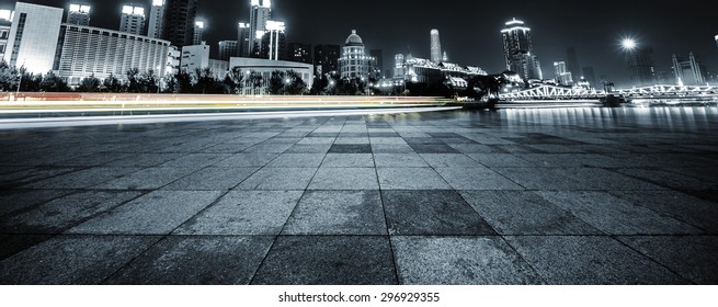 light trails and cityscape with empty road floor