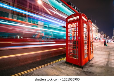 Light trails of a double decker bus next to the iconic telephone booth in London - Powered by Shutterstock