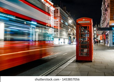 Light trails of a double decker bus next to the iconic telephone booth in London - Powered by Shutterstock