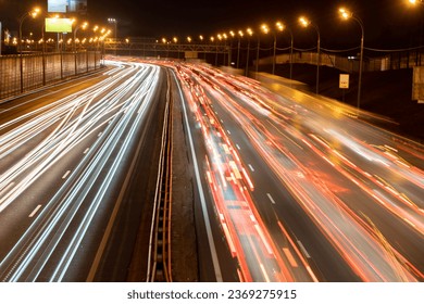 Light trails of headlights and brake lights on a highway; long exposure shot of blurred headlights and brake lights on a two way motorway at night
				