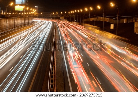 Light trails of headlights and brake lights on a highway; long exposure shot of blurred headlights and brake lights on a two way motorway at night
