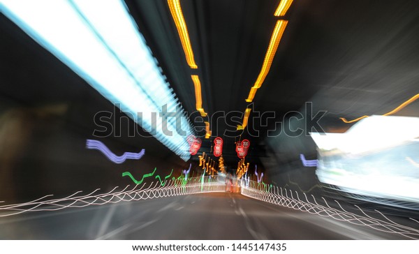 Light trails in tunnel. Art image.\
Long exposure photo taken in a tunnel with 100km speed limit sign.\
Blurry vision, drug abuse, anxiety, while driving\
concept