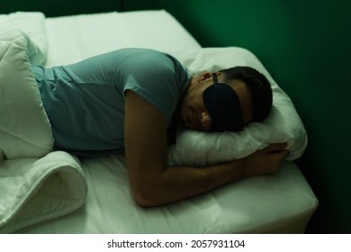 Light Is Uncomfortable. Tired Man With A Sleep Mask Falling Asleep While Hugging His Pillow At Night 