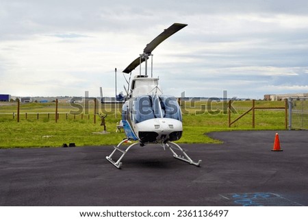 A Light Utility Helicopter Parked at an Airport on a Cloudy Day