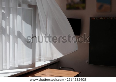A light white curtain sways in the room. A draft i the room on a sunny day. Close-up.