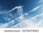 Light white feather clouds in blue sky natural background, diagonal cloud streaks or airplane condensation trail
