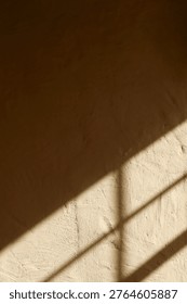 Light from a window creates a pattern of shadows on a textured wall. The scene shows an interplay between light and shadow in a simple indoor space.