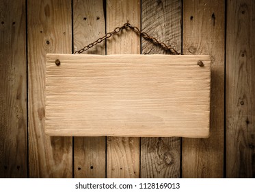 light wood blank singboard hanging on an aged wooden slats wall