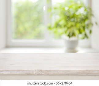 Light wooden table on defocuced spring window background.