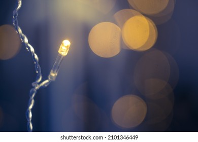 The light of a yellow garland on a blue background with a bokeh. - Shutterstock ID 2101346449