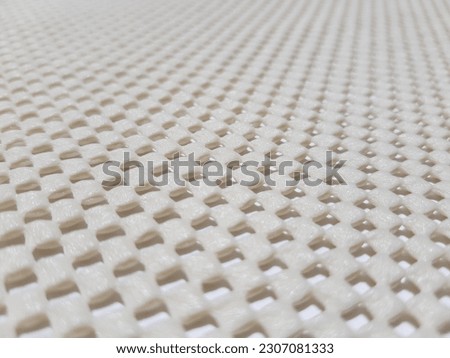 Light yellow, rubberized, mesh, anti-slip carpet underlay - on a white background (macro, slope into the distance, view from an angle, texture).