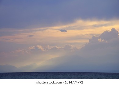 Lightbeams through Clouds over mountain by the sea - calm before the storm