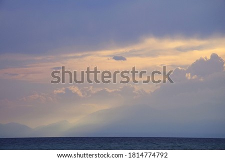 Lightbeams through Clouds over mountain by the sea - calm before the storm