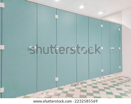 Lightblue toilet cubicles in a row, sanitairy block with nice diamond-shaped floor pattern. Image taken indoor in Leuven, Belgium.