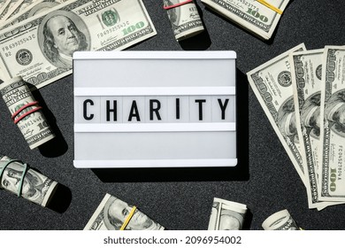 Lightbox board with word CHARITY in black letters around US dollar banknotes. Money, Business, finance, investment, saving. Cash bill. Business budget of wealth and prosperity finance