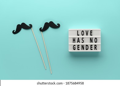 Lightbox with slogan LOVE HAS NO GENDER, props paper mustache on pastel cyan background. Concept Homosexuality, gay love. Top view, creative flat lay. Holiday Greeting card