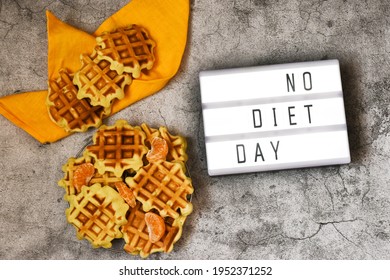 A Lightbox With The Text NO DIET DAY With Viennese Waffles And Yellow Napkin On A Concrete Gray Background. National Day Without Diets.
