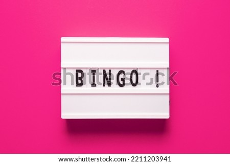 Lightbox with word bingo on pink background, top view. Bingo concept - lottery, casino, win game and jackpot