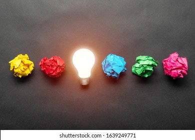Lightbulb and crumpled colorful paper balls on black background. Successful solution of problem. Idea generation and brainstorming. Genius idea among failing ideas metaphor. Business motivation - Shutterstock ID 1639249771