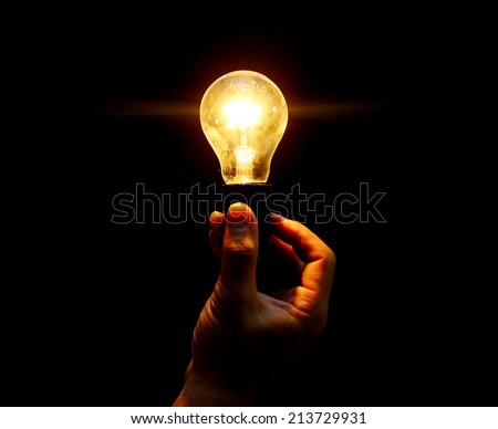 lightbulb held in hand on black background